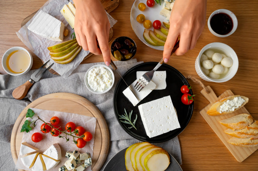 A variety of dairy foods for breakfast, including milk, yogurt, cheese, and a bowl of creamy oatmeal, displayed on a kitchen table.