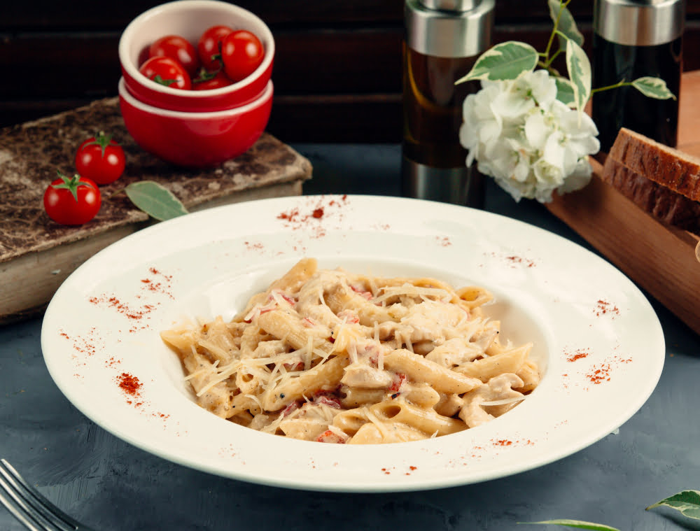 Creamy Marry Me Chicken Pasta served in a white bowl, garnished with fresh basil and Parmesan cheese.